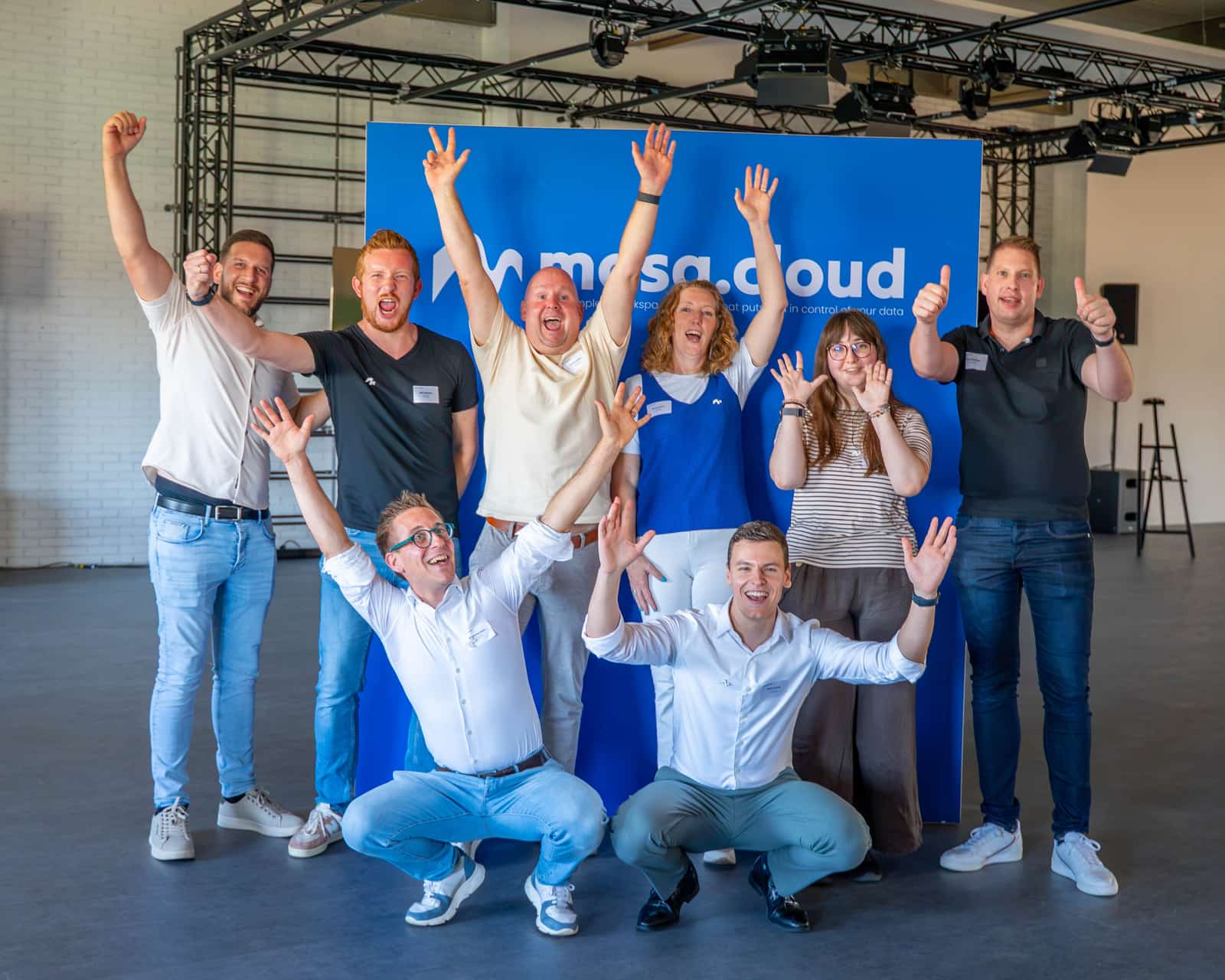 The mosa.cloud team celebrating in front of the mosa.cloud wall